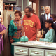 Phylicia Rashad as Clair Huxtable talks on the telephone while Bill Cosby, as Dr. Cliff Huxtable, and other cast members of The Cosby Show gather around during taping of the final episode in New York City on March 6, 1992.